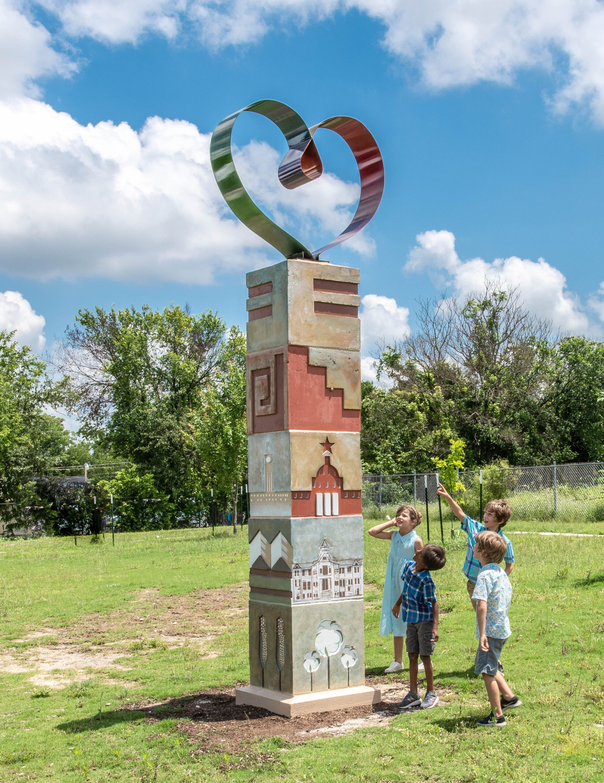 Photograph of the St. John Community Pillar sculpture with children pointing at it in a park.